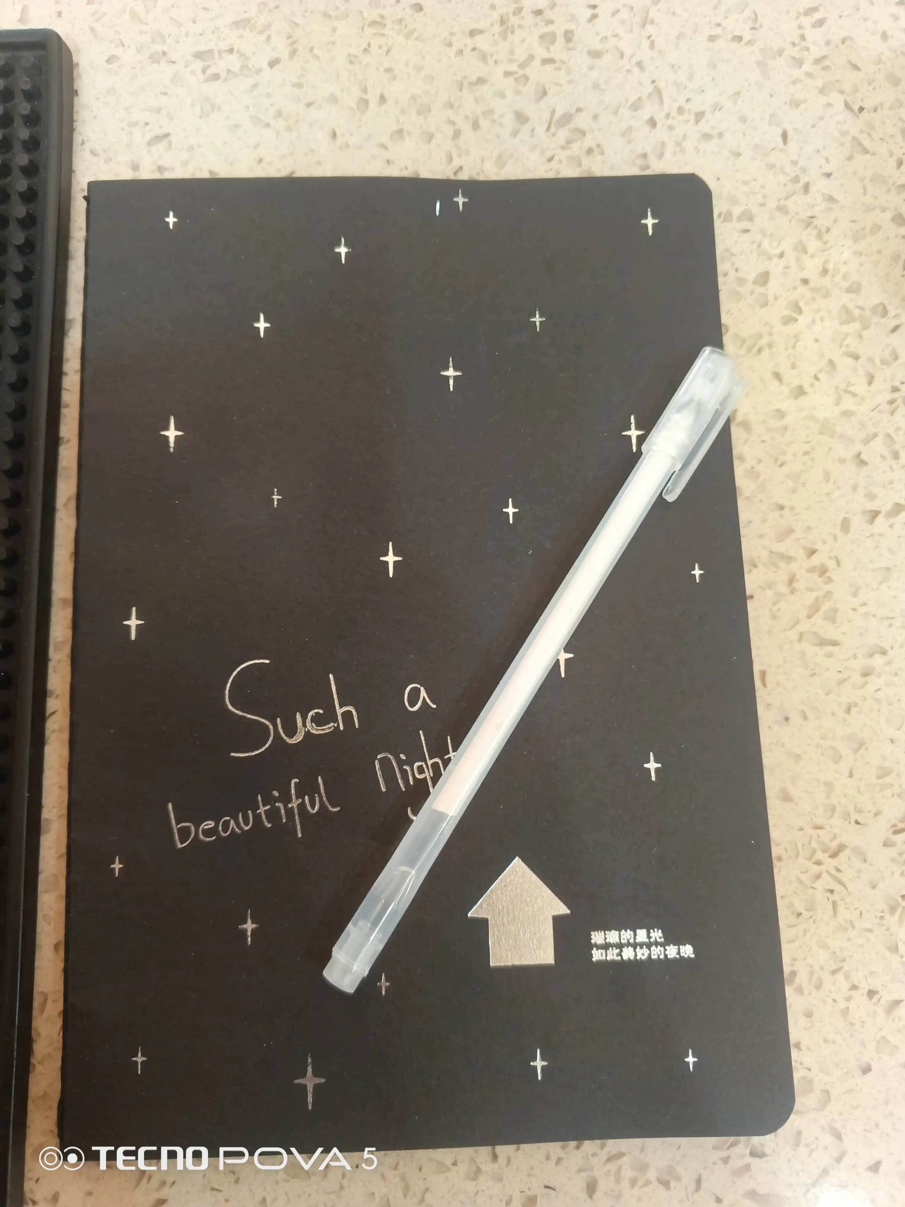 Qora sketchbuk, oq va tilla ruchkasi bilan birga, sketchbuk