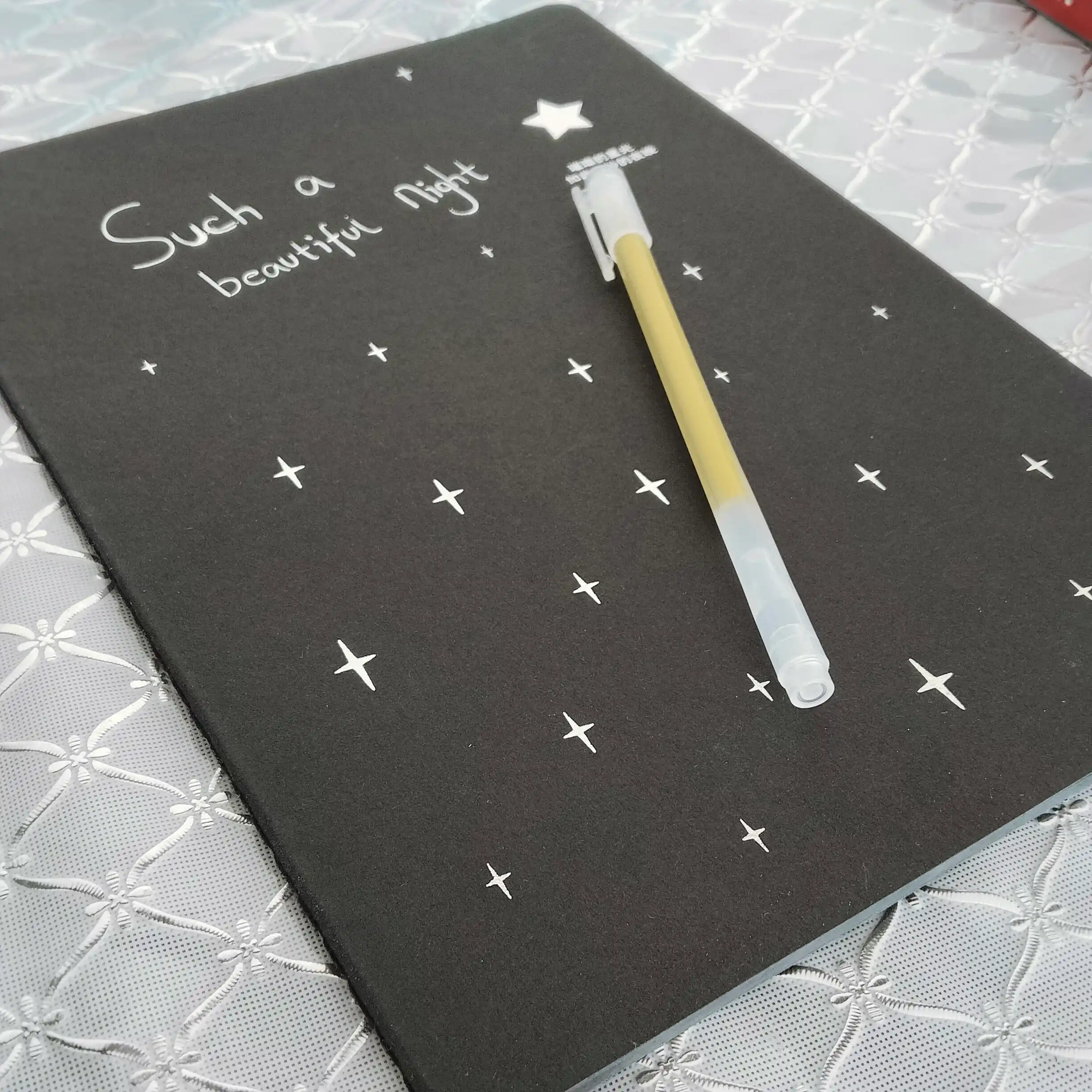 Qora sketchbuk, oq va tilla ruchkasi bilan birga, sketchbuk