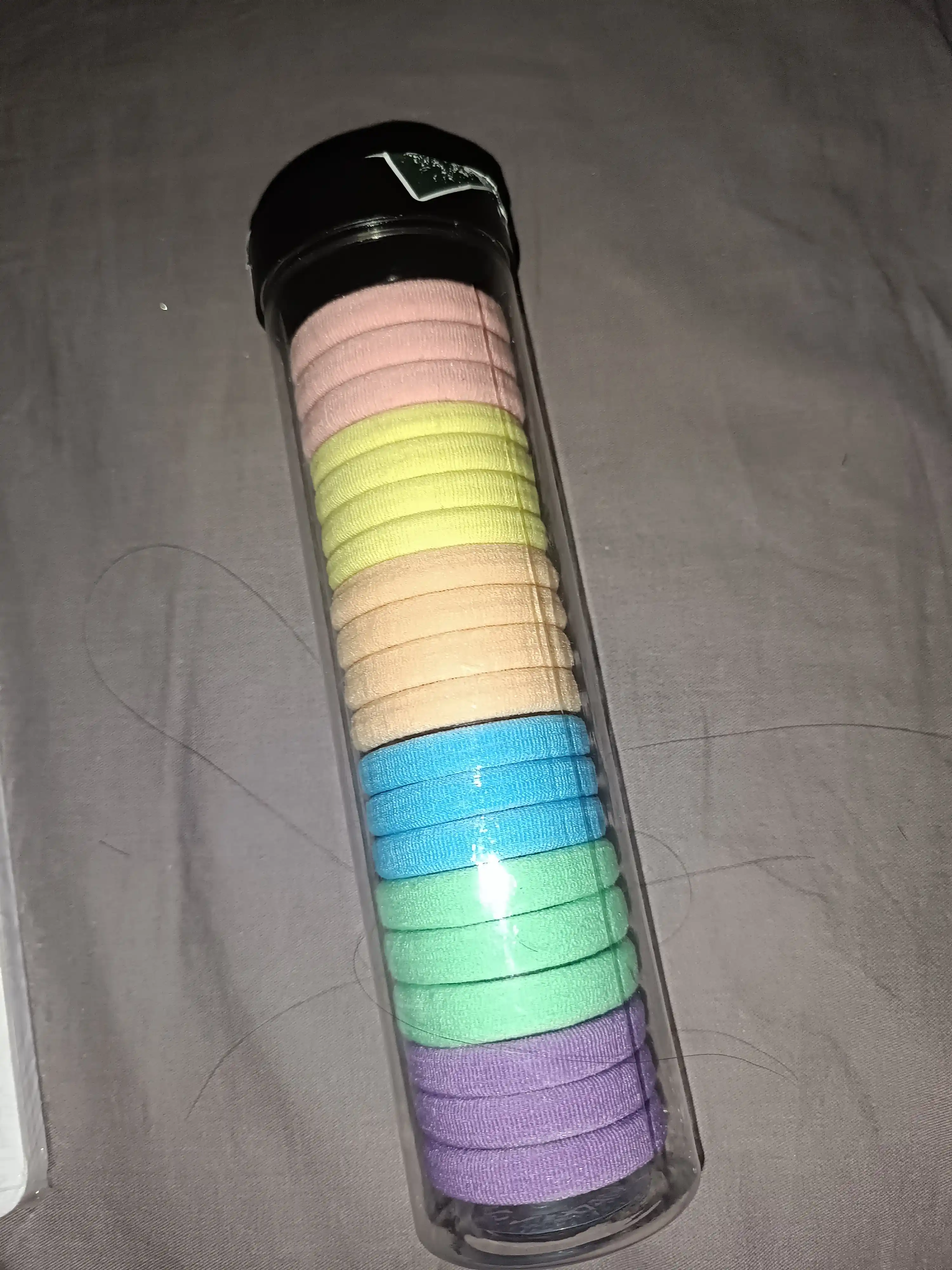 Plastik idishda soch uchun rangli rezinkalar to‘plami